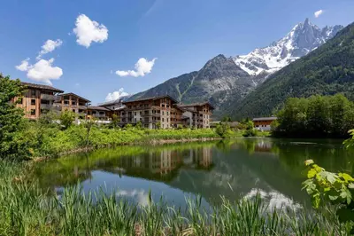 a resort with a lake and mountains in the background at La Cordee 703 Apartment - Chamonix All Year in Chamonix-Mont-Blanc