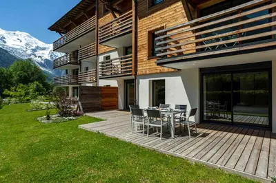 a house with a deck with a table and chairs at La Cordee 703 Apartment - Chamonix All Year in Chamonix-Mont-Blanc