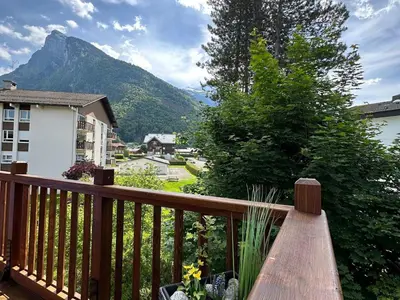 a wooden bench on a balcony with a mountain at Appartement T3 cosy avec balcon au centre de Samoëns - FR-1-624-31 in Samoëns