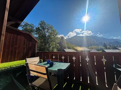 a table and chairs on a balcony with the sun at Appartement en duplex avec piscine à Samoëns - FR-1-624-12 in Samoëns