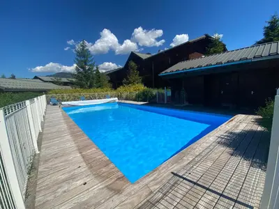 a swimming pool with a wooden deck next to a house at Appartement en duplex avec piscine à Samoëns - FR-1-624-12 in Samoëns