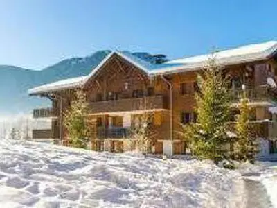 a large wooden house in the snow with mountains at Appartement en duplex avec piscine à Samoëns - FR-1-624-12 in Samoëns