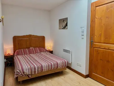 a small bedroom with a bed and a wooden door at Appartement en duplex avec piscine à Samoëns - FR-1-624-12 in Samoëns