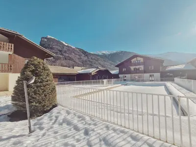 a fence in the snow next to a house at Appartement calme avec piscines chauffée et extérieure - FR-1-624-29 in Samoëns