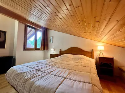 a bedroom with a large bed with a wooden ceiling at Appartement calme avec piscines chauffée et extérieure - FR-1-624-29 in Samoëns