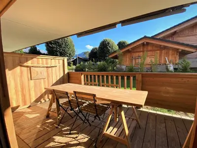 a wooden table and chairs on a wooden deck at Charmant T3 au cœur de Samoëns avec jardin, parking et proche ski-bus - FR-1-624-16 in Samoëns