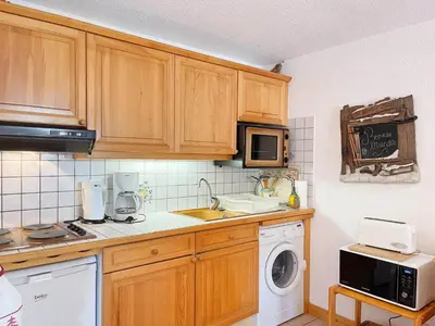 a kitchen with wooden cabinets and a sink and a microwave at Appartement T2 au cœur du village avec parking - FR-1-624-20 in Samoëns