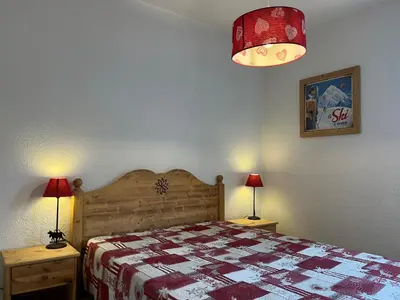 a bedroom with a bed with a red and white quilt at Bel Appartement Central avec Terrasse en Plein Cœur de Samoëns - FR-1-624-19 in Samoëns