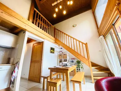 a room with a wooden ceiling with a table and a plant at Duplex chaleureux près télécabine, balcon & WIFI - FR-1-624-33 in Samoëns