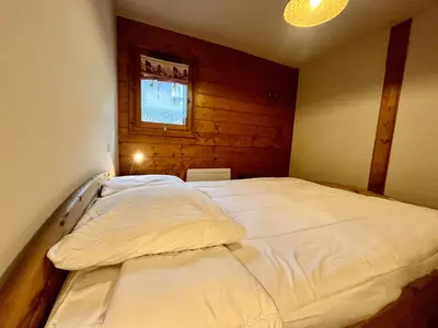 a large white bed in a room with a window at Appartement T3 au cœur de Samoëns avec terrasse et garage - FR-1-624-28 in Samoëns