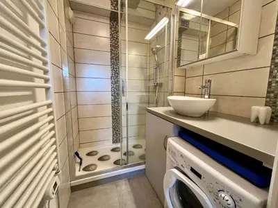 a bathroom with a shower and a sink and a washing machine at Bel appartement moderne avec balcon et parking - FR-1-624-59 in Samoëns