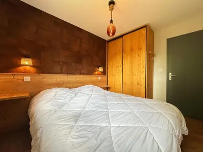 a bedroom with a large bed with a wooden wall at Cosy appartement avec jardin privé et WIFI à Samoëns - FR-1-624-47 in Samoëns