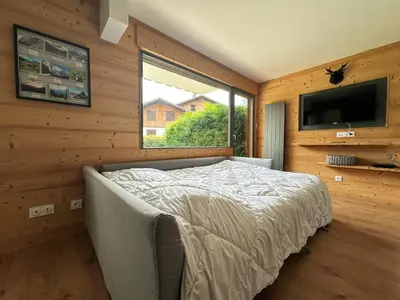 a bedroom with a bed and a tv and a window at Cosy appartement avec jardin privé et WIFI à Samoëns - FR-1-624-47 in Samoëns