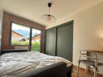 a bedroom with a bed and a window and a chair at Cosy appartement avec jardin privé et WIFI à Samoëns - FR-1-624-47 in Samoëns