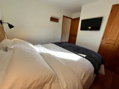 a bedroom with a white bed with a television on the wall at Appartement T3 au cœur de Samoëns avec balcon et parking privatif - FR-1-624-54 in Samoëns