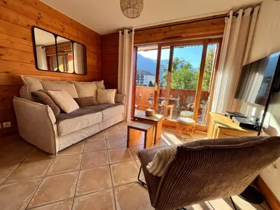 a living room with a couch and a large window at Appartement T3 au cœur de Samoëns avec balcon et parking privatif - FR-1-624-54 in Samoëns
