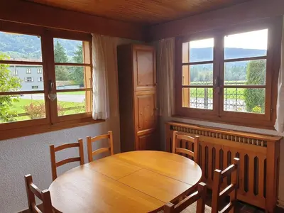 a dining room with a wooden table and three windows at Appartement chalet calme, proche centre, animaux acceptés - FR-1-624-45 in Samoëns