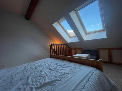 a bedroom with a bed and two windows at Studio duplex lumineux au centre de Samoëns avec parking - FR-1-624-58 in Samoëns