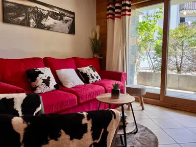 a red couch in a living room with a window at Superbe appartement au centre de Samoëns avec terrasse - FR-1-624-46 in Samoëns