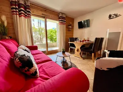 a living room with a red couch and a table at Superbe appartement au centre de Samoëns avec terrasse - FR-1-624-46 in Samoëns