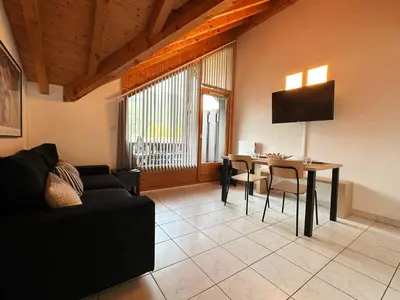 a living room with a black couch and a table at Charmant T2 en centre-ville avec balcon et animaux acceptés - FR-1-624-43 in Samoëns