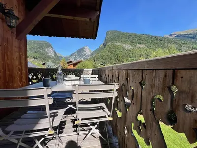 a table and chairs on a deck with mountains in the background at Appartement T3 confortable proche centre avec balcon et parking - FR-1-624-42 in Samoëns