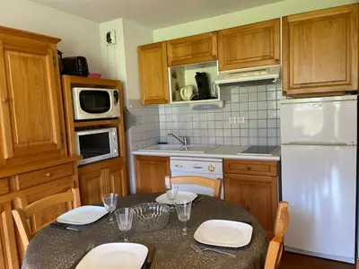 a kitchen with a table and a white refrigerator at Appartement T2 avec Balcon et Parking à Samoëns - FR-1-624-37 in Samoëns