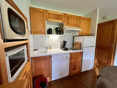 a small kitchen with wooden cabinets and white appliances at Appartement T2 avec Balcon et Parking à Samoëns - FR-1-624-37 in Samoëns