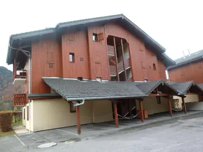 a large red building with a metal roof at Appartement T2 avec Balcon et Parking à Samoëns - FR-1-624-37 in Samoëns