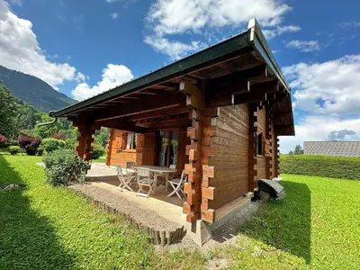a small wooden cabin with a table in a field at Chalet familial avec jardin et cheminée, animaux acceptés - FR-1-624-67 in Samoëns