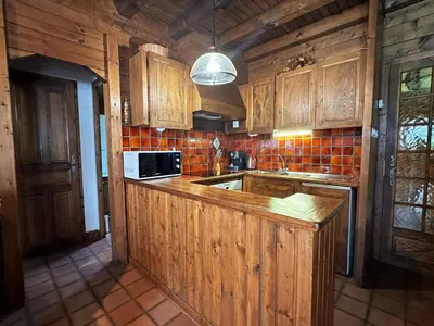 a kitchen with wooden cabinets and a microwave at Chalet familial avec jardin et cheminée, animaux acceptés - FR-1-624-67 in Samoëns