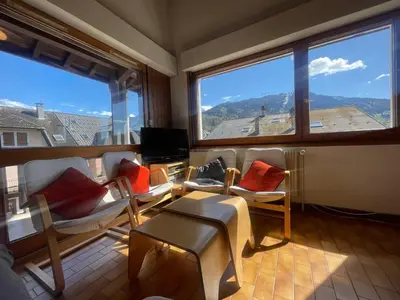 a living room with chairs and a tv and large windows at Duplex familial cœur de village, animaux admis - FR-1-624-1 in Samoëns