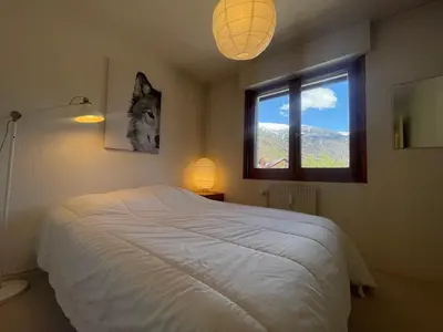 a bedroom with a white bed and a window at Duplex familial cœur de village, animaux admis - FR-1-624-1 in Samoëns