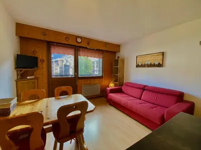 a living room with a red couch and a table at Studio lumineux au centre de Samoëns, vue sur Le Criou - FR-1-624-52 in Samoëns