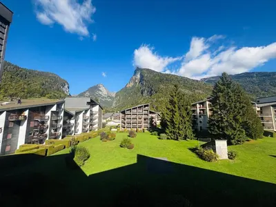 an apartment complex with a green yard with mountains in the background at Studio lumineux au centre de Samoëns, vue sur Le Criou - FR-1-624-52 in Samoëns