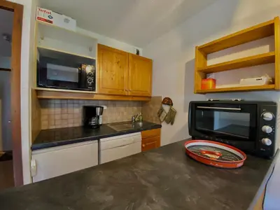 a kitchen with a microwave and a black counter top at Studio lumineux au centre de Samoëns, vue sur Le Criou - FR-1-624-52 in Samoëns