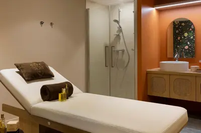 a bathroom with a shower and a bed and a sink at RockyPop Flaine Hotel & Spa in Flaine