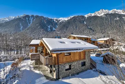 a log home in the snow with mountains in the background at Chalet Breitalps in Chamonix-Mont-Blanc