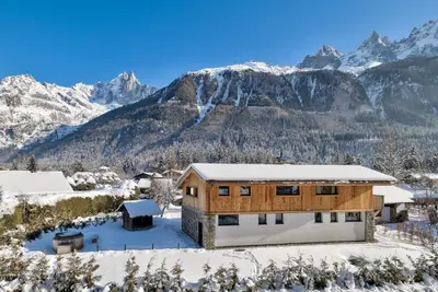 a house in the snow with mountains in the background at Chalet Breitalps in Chamonix-Mont-Blanc