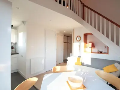 a living room with a staircase and a table and chairs at Duplex 2P/4 avec Balcon, WIFI et Parking Les Carroz - FR-1-572-15 in Les Carroz d'Araches