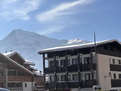 a building with a snow covered mountain in the background at Charme au centre d'Arâches : 2 pièces + coin montagne, 4/5 pers, proche pistes et commerces - FR-1-572-154 in Les Carroz d'Araches