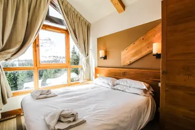 a bedroom with a large bed with a window at Cosy, modern 2-bed with fireplace & beautiful views in Flaine