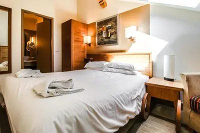 a bedroom with a large white bed and a chair at Cosy, modern 2-bed with fireplace & beautiful views in Flaine