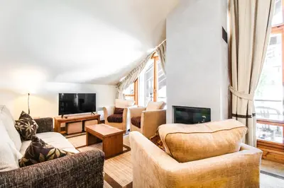 a living room with couches and a tv at Cosy, modern 2-bed with fireplace & beautiful views in Flaine