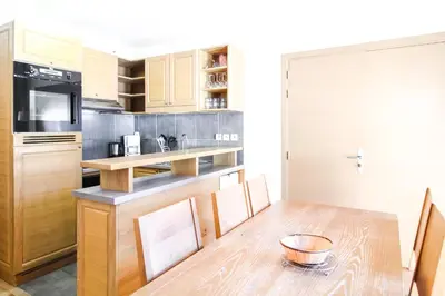 a kitchen with a wooden table and a dining room at Charming 6th-floor 2-bedroom apartment with fireplace in Flaine