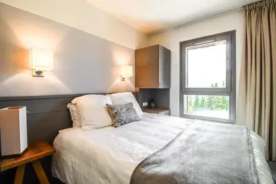 a bedroom with a large bed with a window at South-facing renovated 2-bed apartment Les Terrasses d'Eos in Flaine