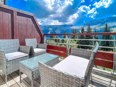 a balcony with chairs and tables and a view of mountains at Bright, spacious South-facing 1-bedroom apartment in Flaine