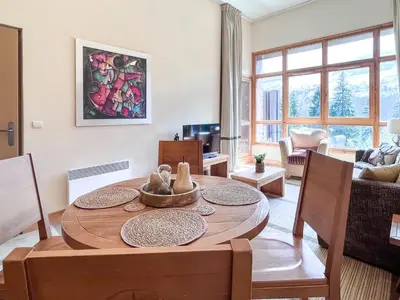 a living room with a dining room table with chairs at Bright, spacious South-facing 1-bedroom apartment in Flaine