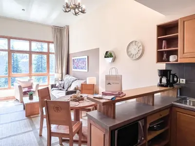 a kitchen and living room with a table and a couch at Bright, spacious South-facing 1-bedroom apartment in Flaine