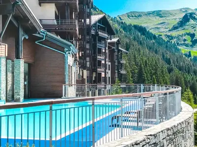 a hotel with a swimming pool in front of a mountain at Bright, spacious South-facing 1-bedroom apartment in Flaine